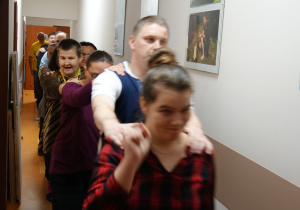 Grupa osób ustawionych jedna za drugą trzymając się za ramiona bierze udział w zabawie w tworzenie pociągu.