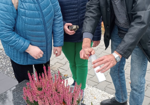 Grupa osób odpala znicz.