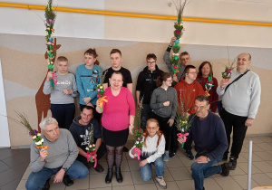 Zdjęcie grupowe osób. Każda z osób trzyma w rękach wykonana palmę wielkanocną.