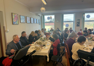 Duża grupa osób siedząca przy świątecznym stole.