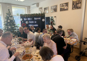 Grupa osób siedząca przy świątecznym stole.