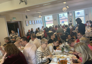 Duże grupy osób siedzących przy świątecznych stołach.