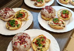 Białe talerze, na których znajdują się pączki i zapiekanki.