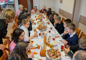 Duża grupa osób siedząca przy suto stole.