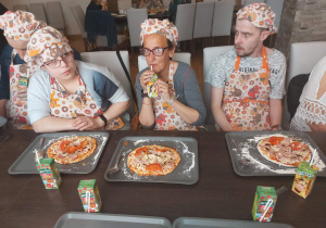 dwie kobiety i mężczyżna siedzą przy pizzy