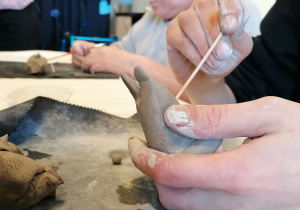 dłonie obrabiające figurkę z gliny