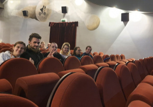 Grupa zadowolonych osób siedzących w fotelach kinowych pozuje do zdjęcia